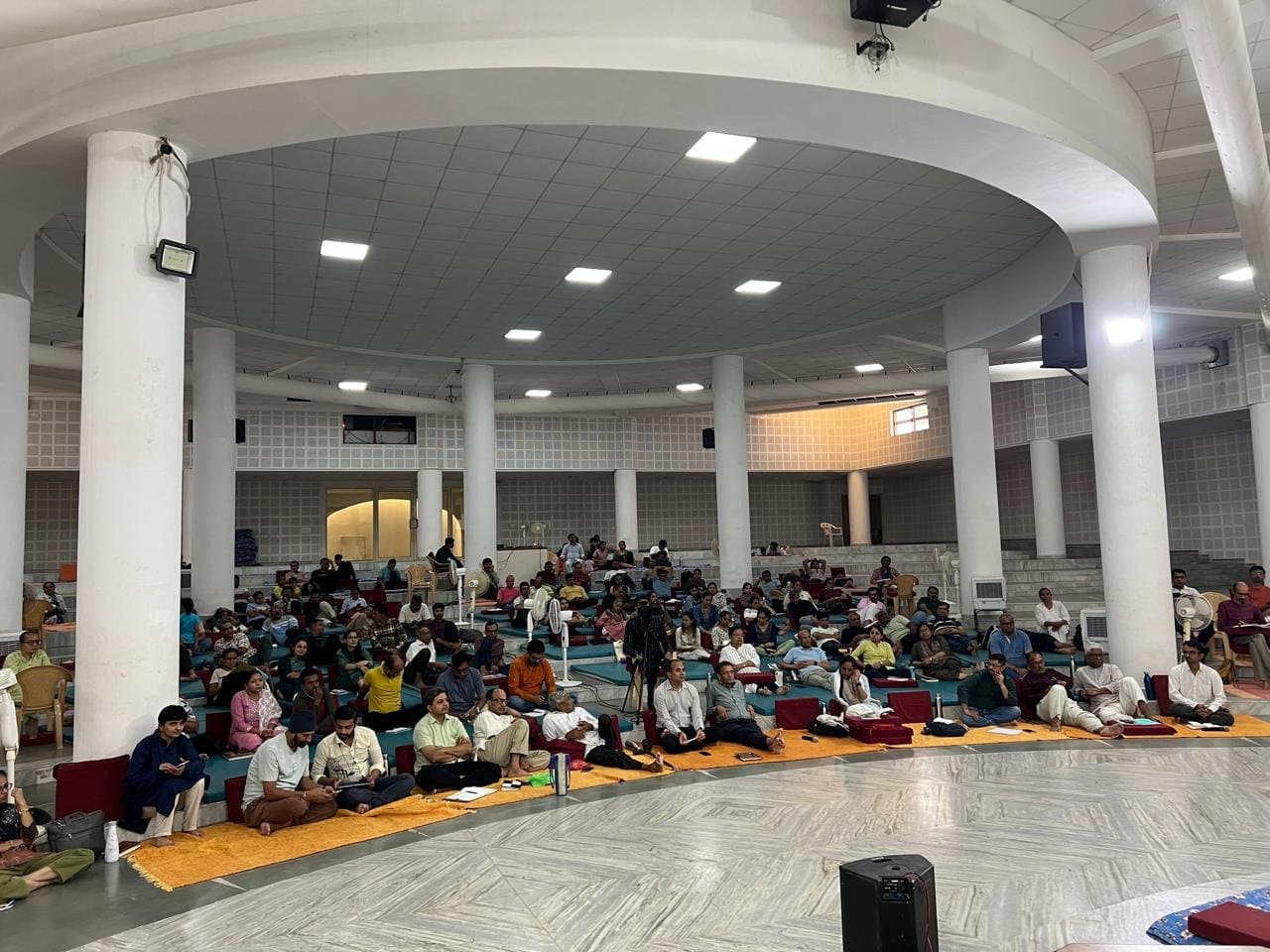 A large gathering seated in a domed hall
