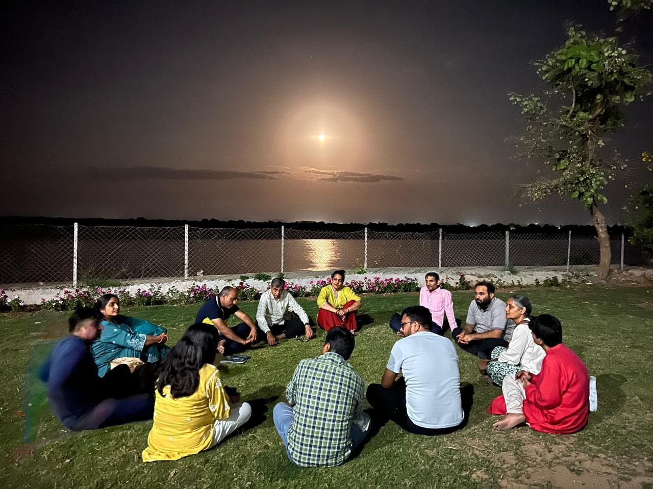 A group seated in a circle under moonlight