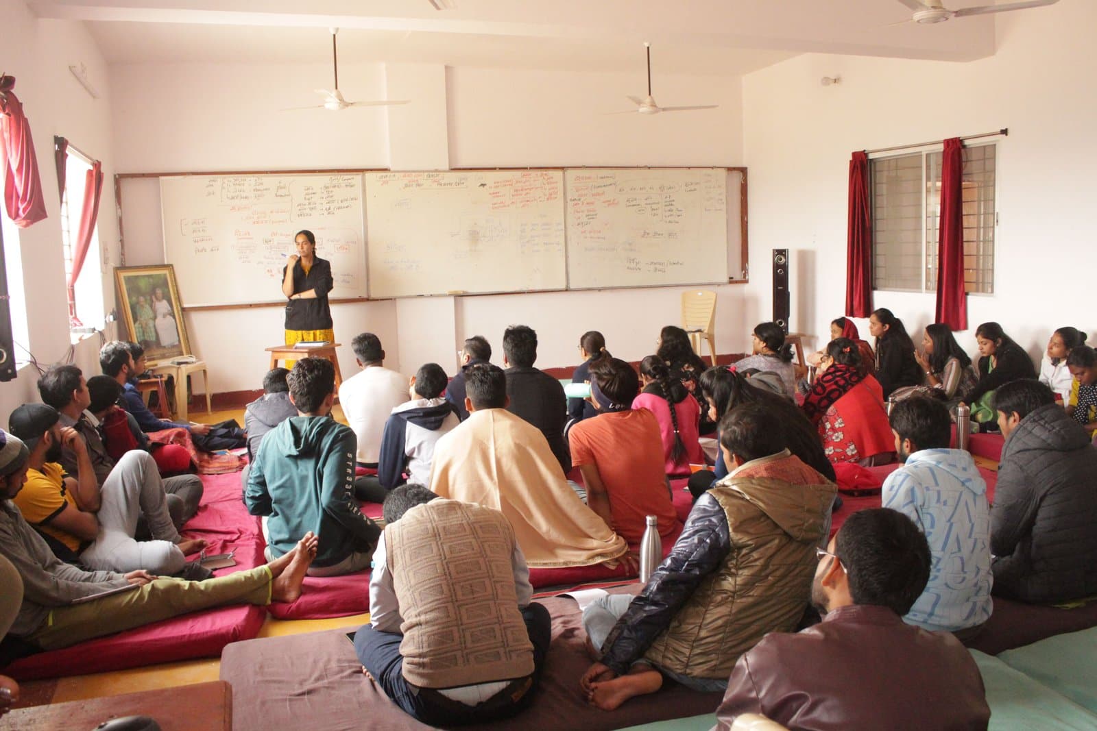 A facilitator leading a workshop discussion with participants seated on the floor